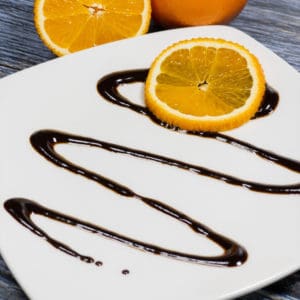 chocolate orange balsamic glaze drizzled on a plate with oranges