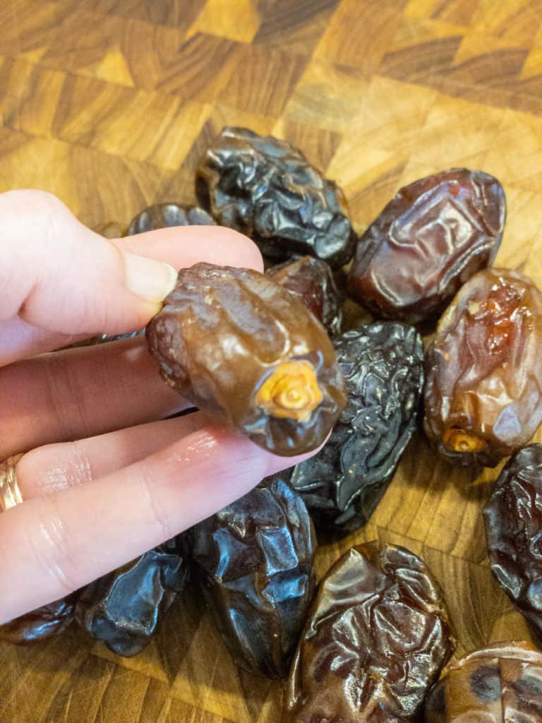 Medjool dates in hand showing dried flower part