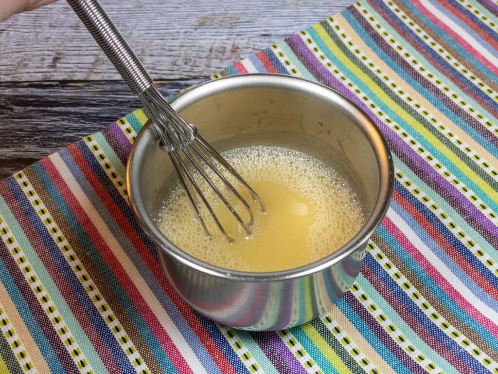 Whisking Simple Summertime Salad Dressing ingredients in a small metal bowl