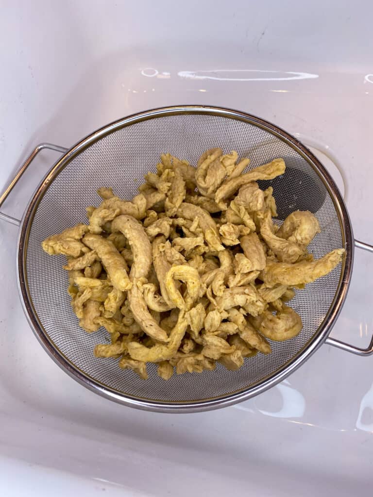 soaked soy curls draining in colander in white sink