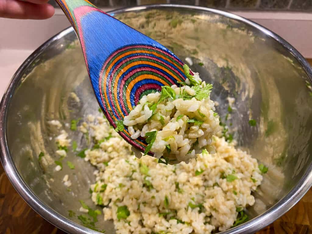 Closeup of Cilantro Lime Brown Rice on Brightly Colored Wooden Spoon over Bowl.
