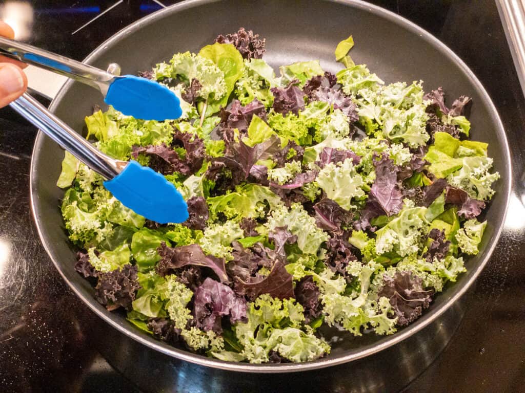 kale and swiss chard in nonstick pan with tongs