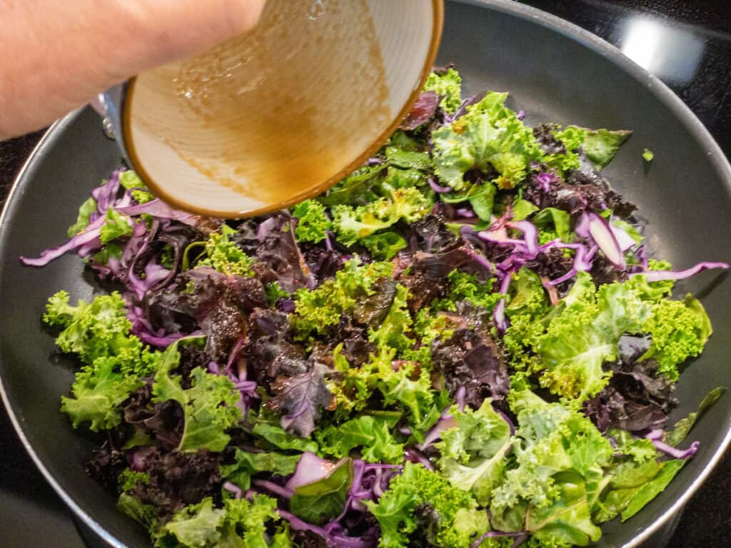 bowl of sauce poured over greens in nonstick pan