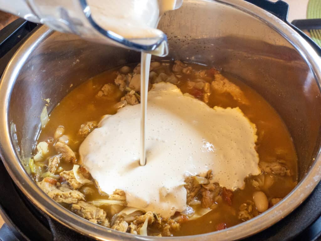 Savory Cashew Cream Sauce being poured into taco soup